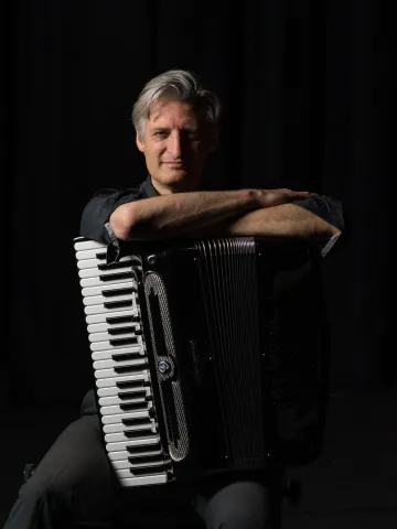 Anthony with his accordian in a black space